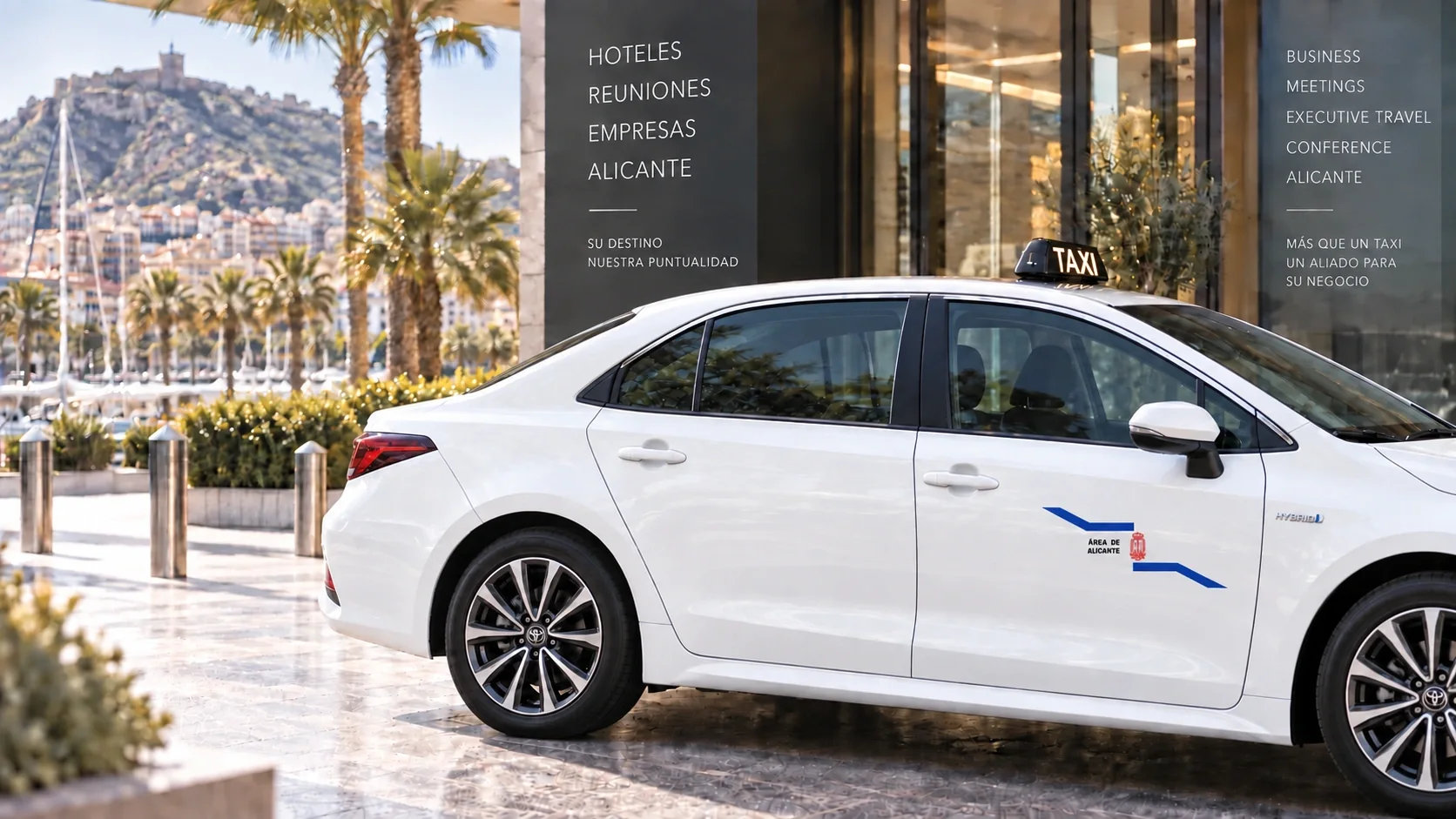 Taxi blanco TAXIÓN junto a la entrada de un edificio de empresas en Alicante